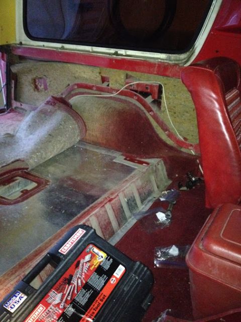 1978 Ford Bronco - The interior of a vehicle is shown, with red upholstery and exposed metal flooring, alongside a Craftsman tool set.