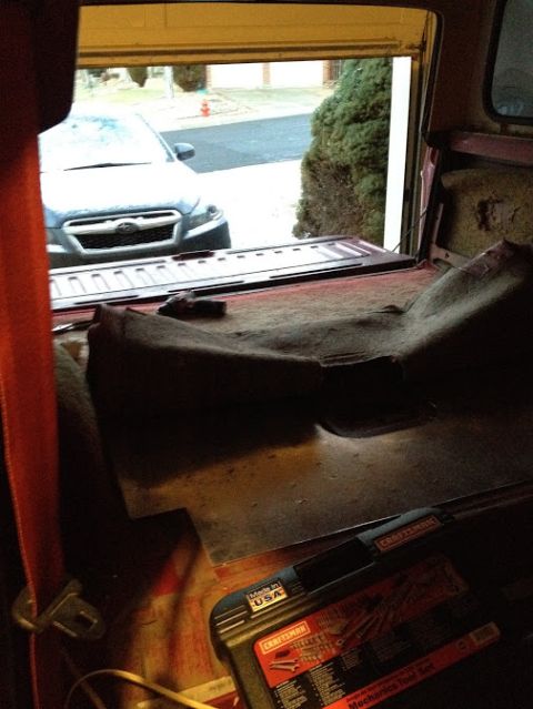 1978 Ford Bronco - The interior of a vehicle shows a view of another car parked outside through an open garage door.