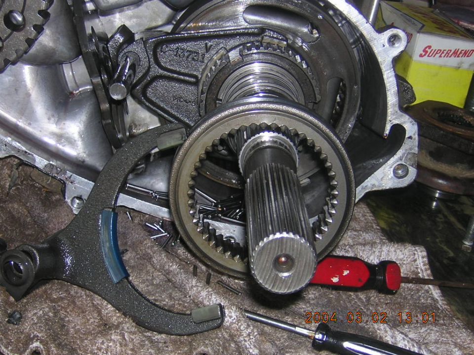 Disassembled transmission with splined shaft, gears and tools on a workbench