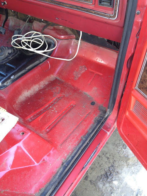 Red vehicle interior floor with a coiled white wire and a black gear shifter