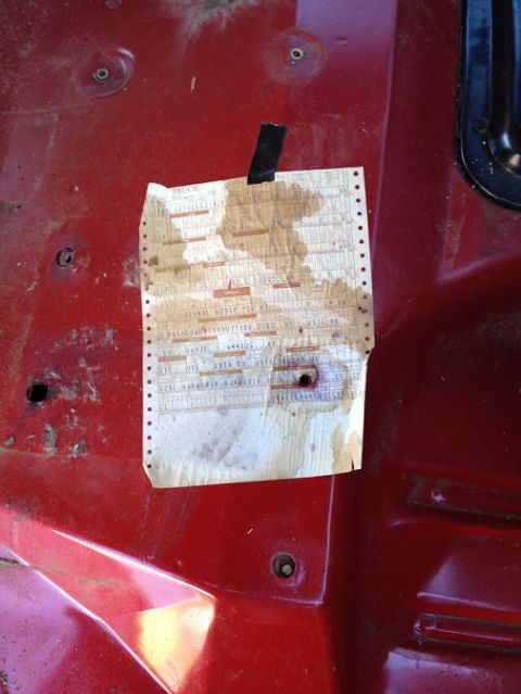 1978 Ford Bronco - A stained paper document is taped to a red metal surface, showing some printed text.