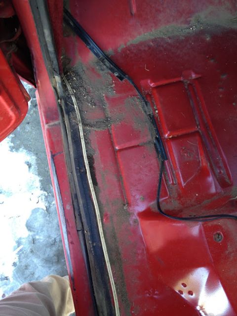 1978 Ford Bronco - Interior view of a vehicle's floor pan and door jamb area, showing dirt and wiring.