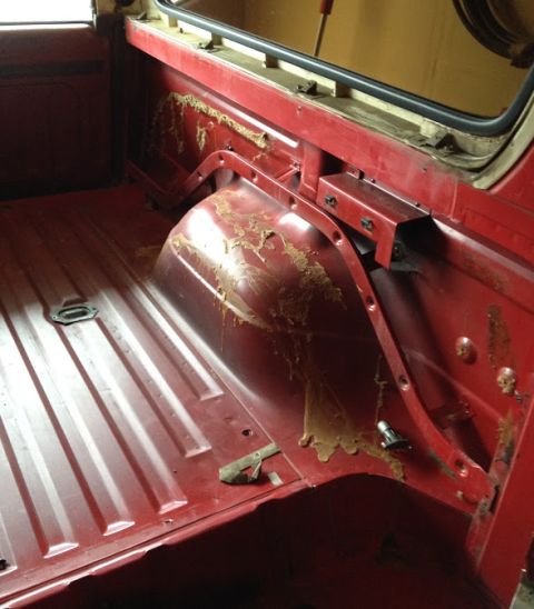 1978 Ford Bronco - The interior of a red truck bed shows some dried residue on the wheel well and side panel.