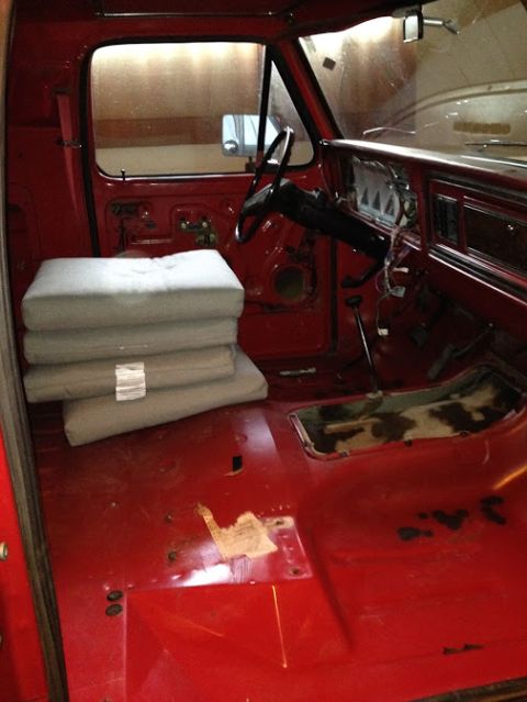 1978 Ford Bronco - The interior of a red truck is shown with the floor and dashboard exposed, ready for restoration.