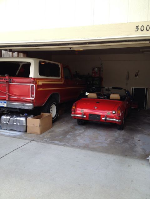 1978 Ford Bronco - A red 1978 Ford Bronco and a red convertible are parked inside a garage.