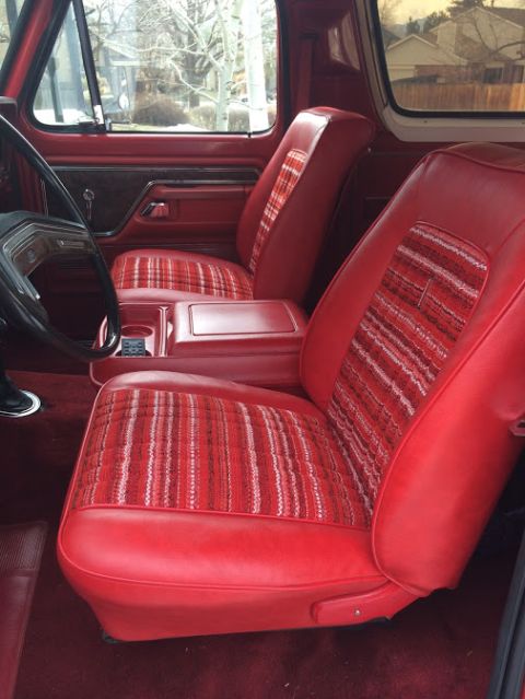1978 Ford Bronco - The interior of a 1978 Ford Bronco features red vinyl seats with distinctive plaid fabric inserts.