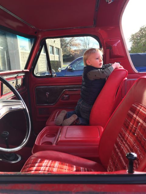 1978 Ford Bronco - A young child sits on the center console inside a red 1978 Ford Bronco.