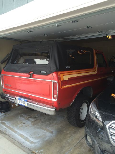 1978 Ford Bronco - Rear view of a red 1978 Ford Bronco with a black soft top and distinctive stripe decals.