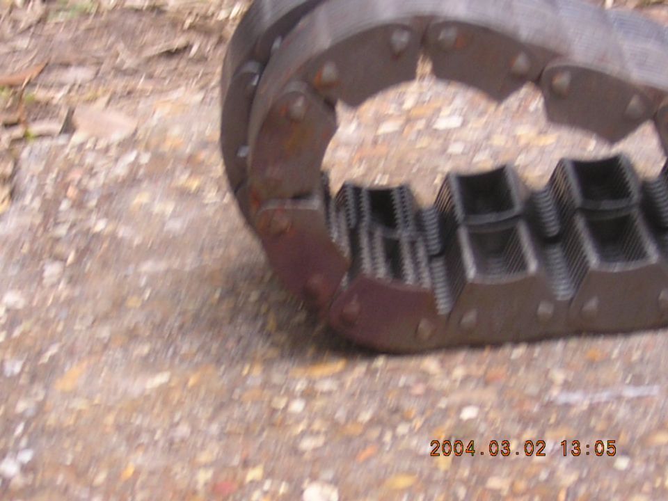 Rusted riveted metal clutch or spring assembly resting on gravel ground