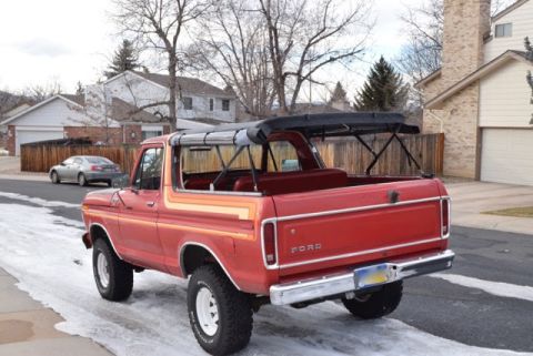 1978 Ford Bronco - Rear view of a red 1978 Ford Bronco with a black soft top parked on a snowy street.