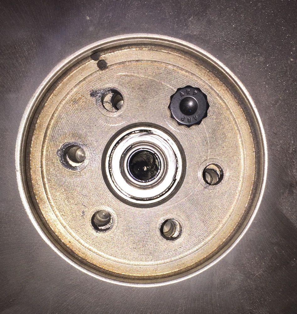 Close-up of a clock mechanism with a small black adjustment knob and visible gears