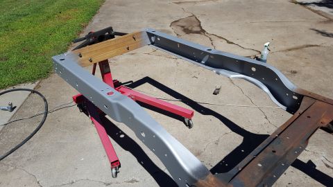1994 Ford Bronco - A vehicle frame is being worked on, with some parts painted and others showing rust.