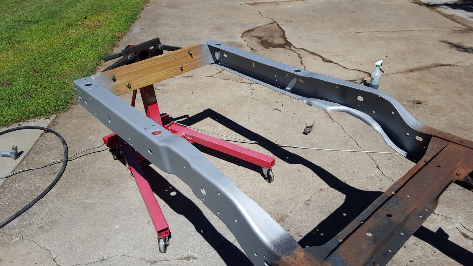 vehicle frame on red stands, partially painted gray