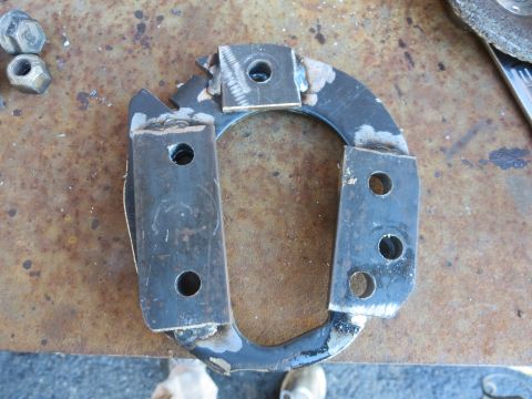 1990 Ford F-250 - A close-up view of a fabricated metal component with welded brackets and drilled holes.