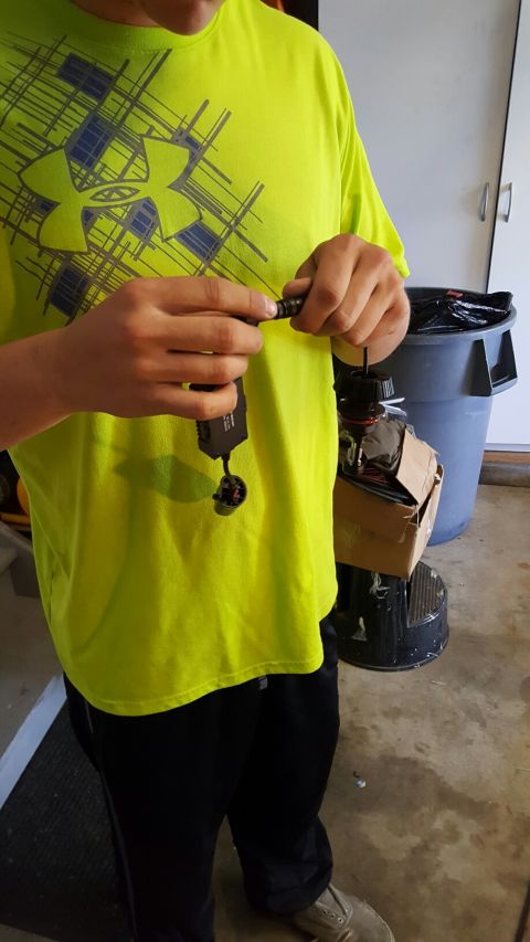 1996 Ford Bronco - A person holds a car part that has wires and a makeshift cardboard enclosure.