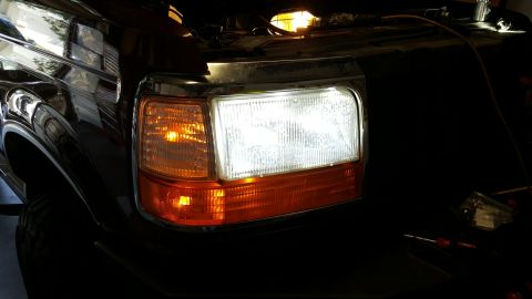 1996 Ford Bronco - Close-up of a black Ford Bronco's front headlight assembly, showing the headlight and amber turn signal.