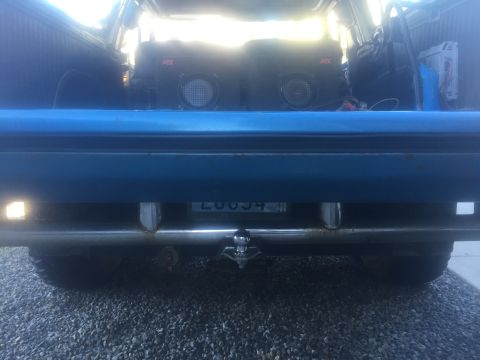 1979 Ford Bronco - Rear view of a blue SUV with a trailer hitch and aftermarket speakers visible inside.