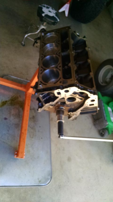 1985 Jeep CJ7 - Engine block on an engine stand, with a torque wrench attached, in a garage setting.