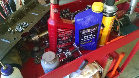 1985 Jeep CJ7 - A collection of engine parts and various automotive fluids are organized in a red toolbox.