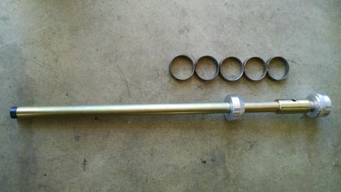 1985 Jeep CJ7 - A metal tool and several rings are laid out on a concrete surface, possibly for a vehicle repair or assembly.
