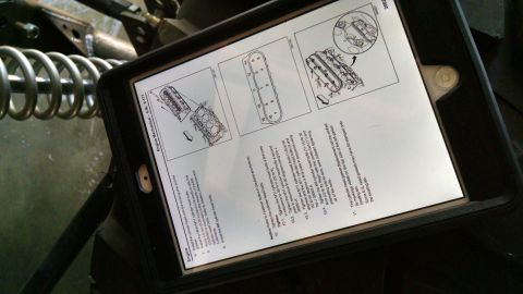 1985 Jeep CJ7 - A tablet displays an engine repair manual, showing diagrams and instructions for engine assembly and maintenance.