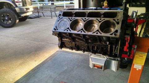 1985 Jeep CJ7 - An engine block sits on a stand in a driveway, with a pickup truck visible in the background.
