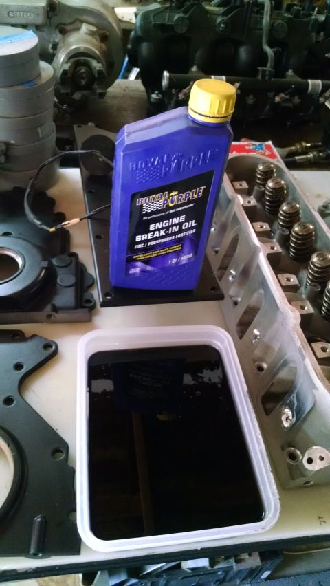 1985 Jeep CJ7 - Engine parts and a bottle of Royal Purple oil are laid out on a workbench.