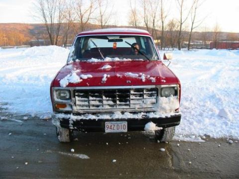 1981 Ford Bronco - Red Ford truck parked in a snowy area, front grille partially obscured by snow.