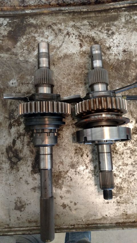 1996 Ford Bronco - Two transmission input shafts with gears and synchronizers are laid out on a metal surface. The shafts appear to be from a Ford Bronco.