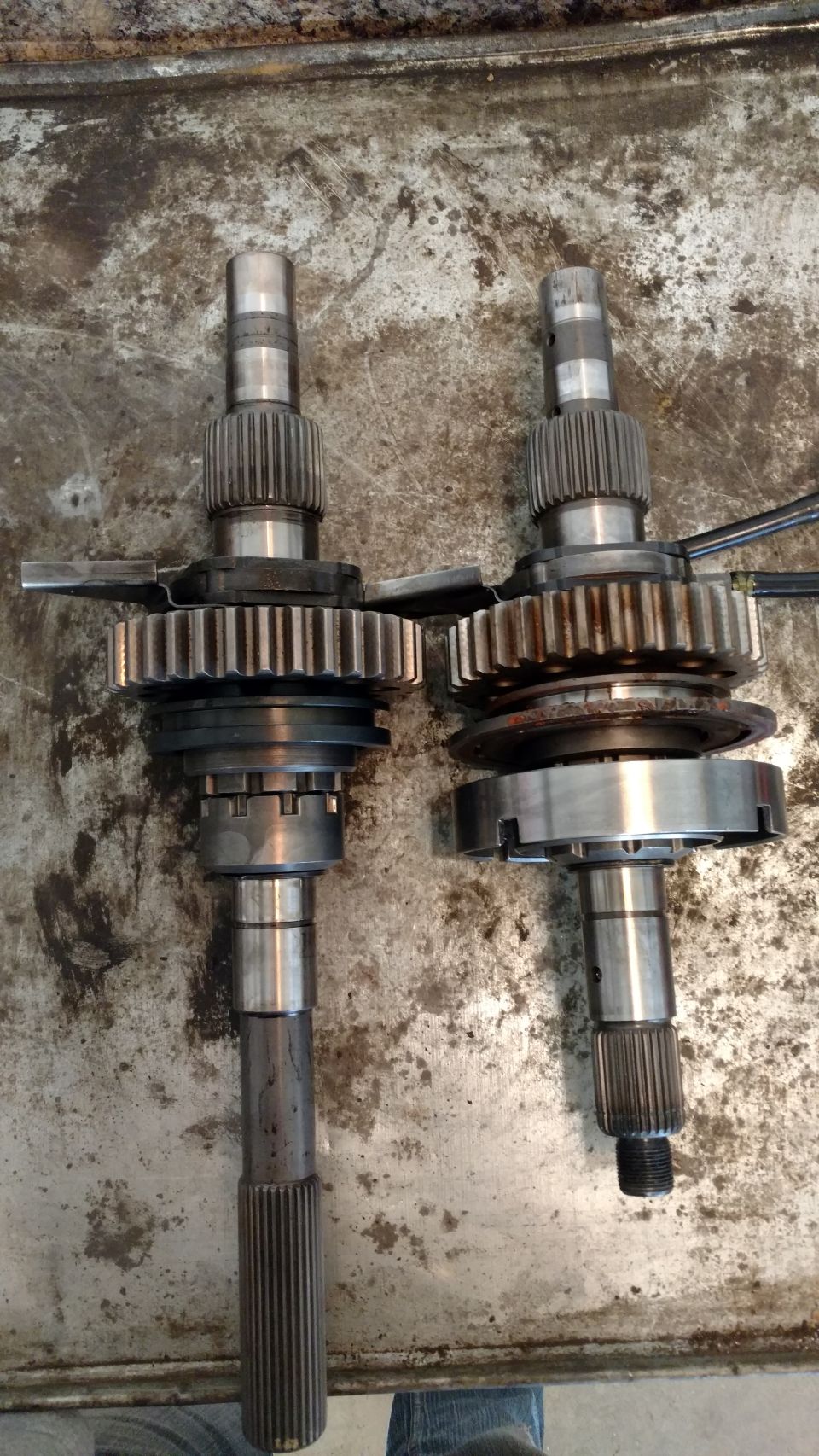 Two transmission input shafts with gears and synchronizers on a metal surface.