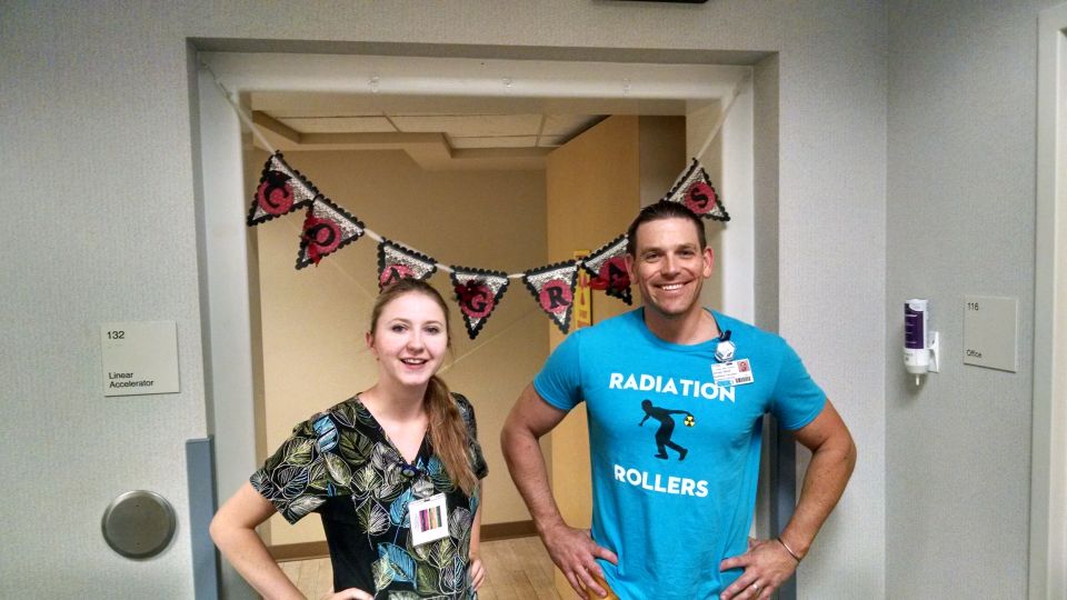 A man and a woman in a hallway with a congratulatory banner.