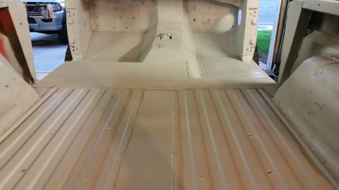 1979 Ford Bronco - The interior floor of a vehicle, likely a Ford Bronco, has been painted a light gray primer. The ribbed metal floor of the cargo area is vi…