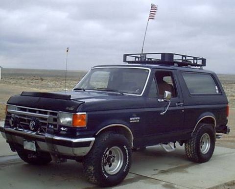 1988 Ford Bronco - This dark blue 1988 Ford Bronco is equipped with a roof rack and an American flag flying from its antenna.