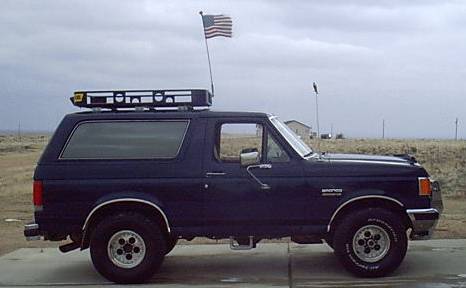 1988 Ford Bronco - This 1988 Ford Bronco is equipped with a roof rack and an American flag mounted on a pole.