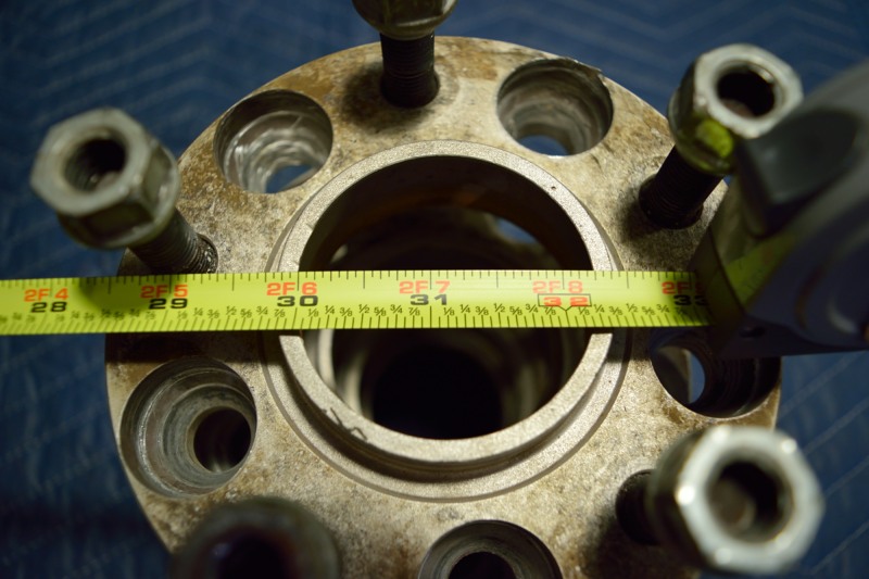 Close-up of a metal wheel spacer with a measuring tape showing approximately 30-32 inches.
