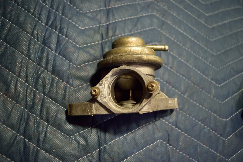 Automotive vacuum actuator or EGR valve on a blue quilted surface.