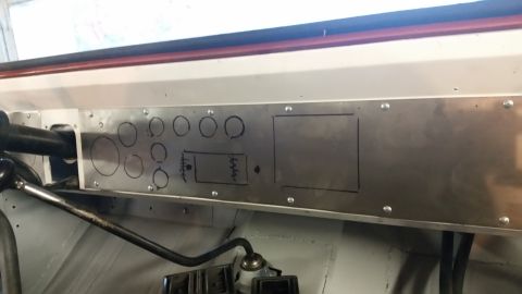 1979 Ford Bronco - A close-up view of a custom metal dashboard panel with hand-drawn circles and rectangles, likely for gauges and switches, on a vehicle.