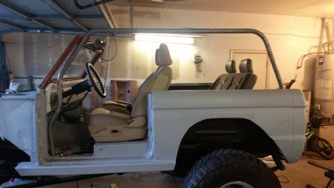 1979 Ford Bronco - The interior of a classic Ford Bronco undergoing restoration is shown, featuring tan bucket seats, a roll cage, and a steering wheel. The v…