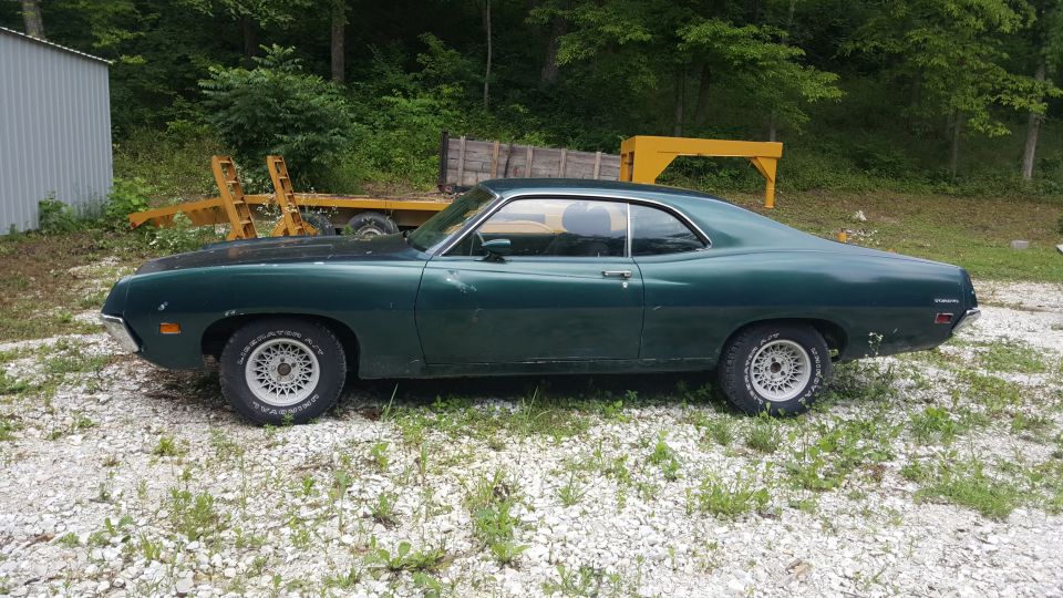 Dark green 1971 Ford Torino coupe parked on gravel.