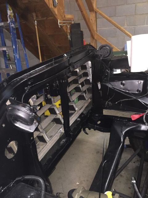 1978 Ford Bronco - A black painted vehicle frame, possibly a 1978 Ford Bronco, is shown in a garage setting. The front grille area and some suspension compone…