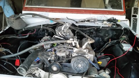 1979 Ford Bronco - The engine bay of a 1979 Ford Bronco is shown, with the engine partially assembled and various wires and hoses connected. The vehicle appea…