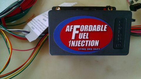 1985 Jeep CJ7 - A close-up view of an aftermarket fuel injection control module with a red and blue oval sticker that reads "AFFORDABLE FUEL INJECTION" and…