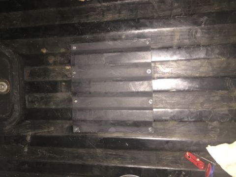 1988 Ford Bronco - A black plastic panel with horizontal ridges is screwed onto the ribbed interior surface of a black vehicle. The panel appears to be a modi…