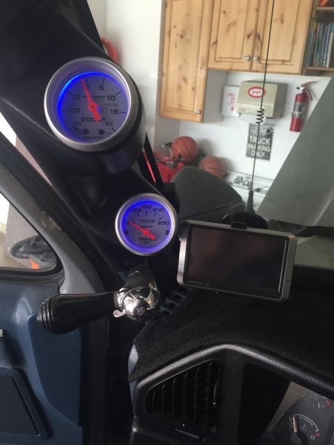 1988 Ford Bronco - The interior of a vehicle shows a dashboard with two gauges, a Garmin GPS unit, and a manual window crank. The gauges are illuminated with…
