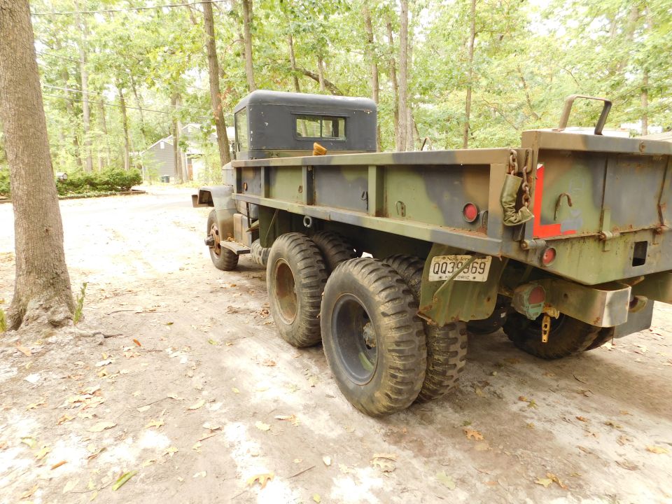 Rear passenger side of a camouflage military dump truck with a NY license plate.