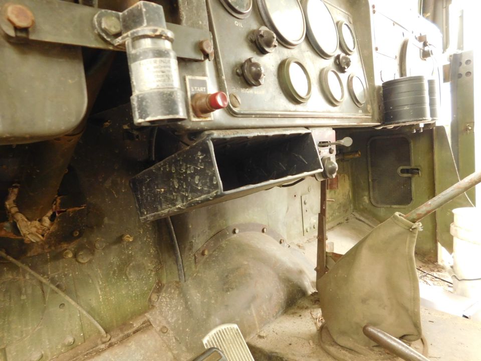 Interior of a military vehicle dashboard with gauges, switches, and gear shifter boot.