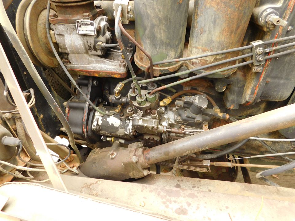 Close-up of a vehicle's engine bay, showing fuel injection system and rusty mechanical parts.