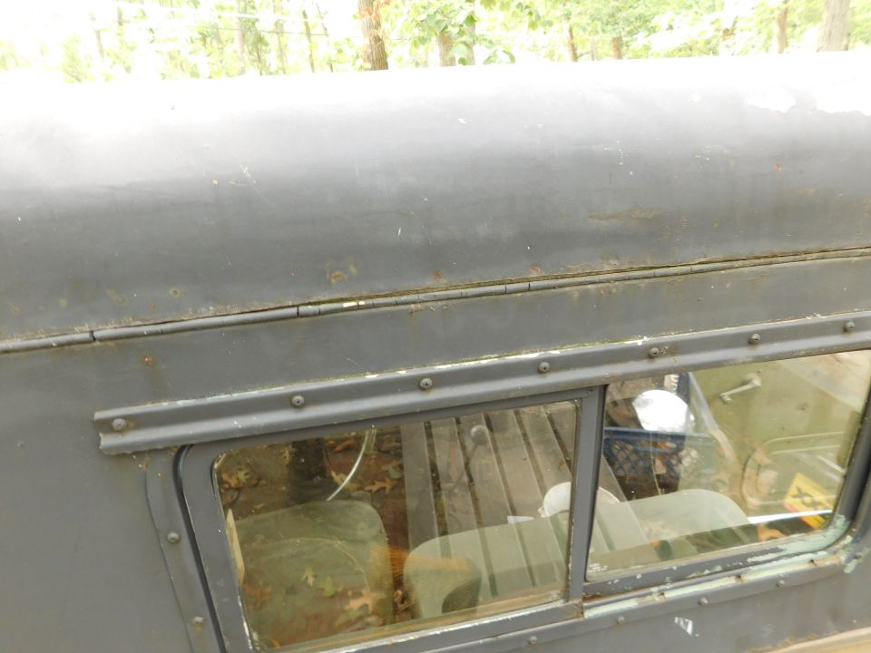 Close-up of dark gray vehicle roof and side window with rust