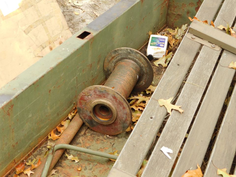 Metal spool in a green container with brake fluid and leaves