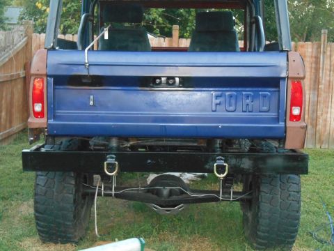 1972 Ford Bronco - The rear of a blue 1972 Ford Bronco shows its "FORD" tailgate and aftermarket black bumper.